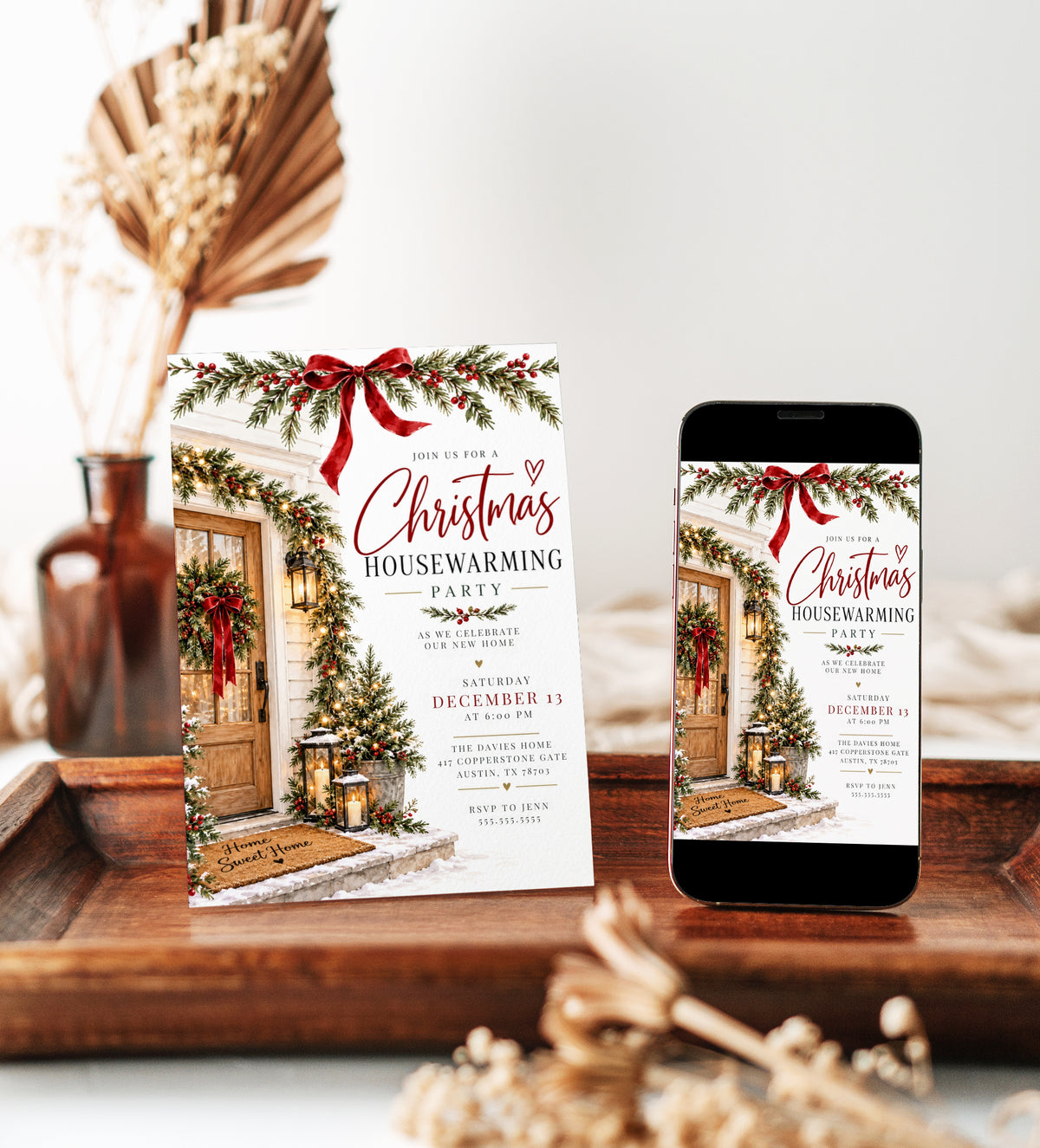 Christmas housewarming party invitation with a wooden front door, evergreen wreath and garlands, red bows, glowing lanterns, snowy steps, and a Home Sweet Home doormat