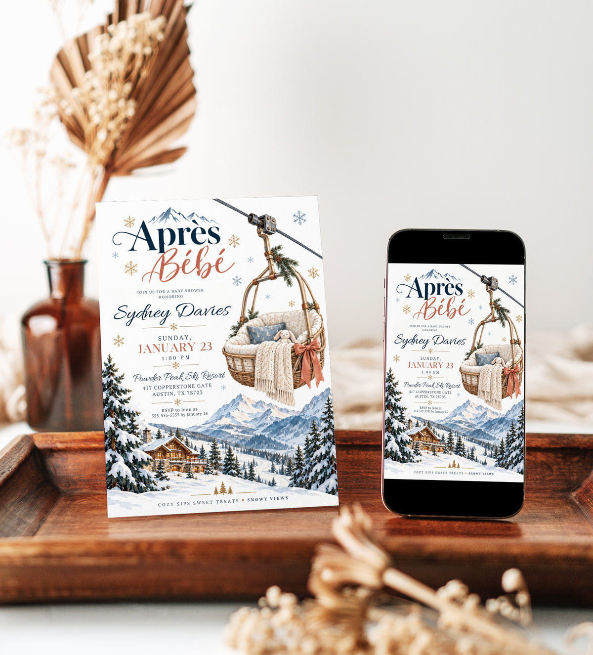 Après Bébé baby shower invitation with a basket-style ski lift holding a plush bunny and knit blanket above snowy mountains, evergreen trees, and a ski chalet