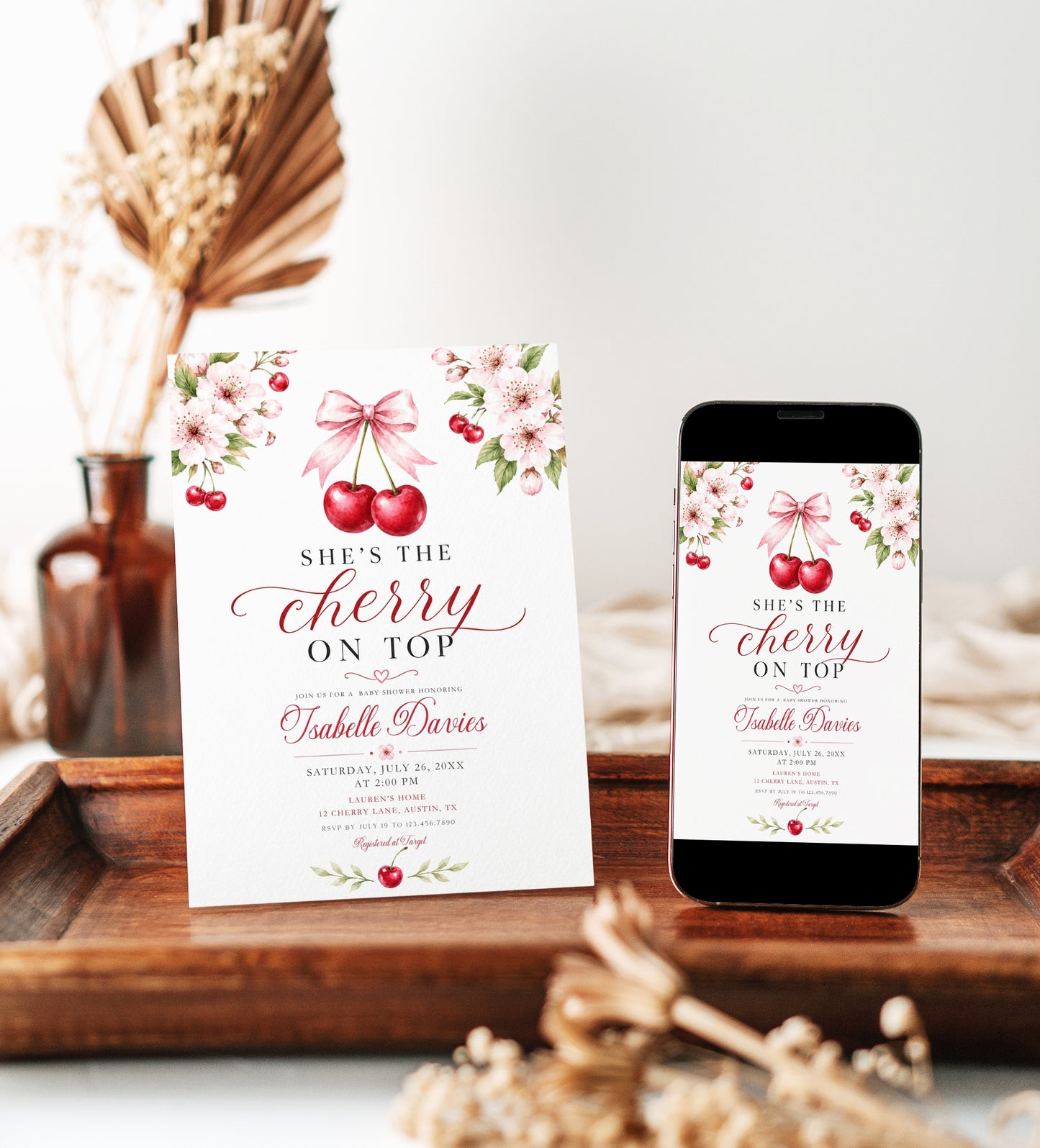 Cherry baby shower invitation with watercolor cherries, pink cherry blossoms, leafy branches, pink bow, elegant script lettering, and clean white background