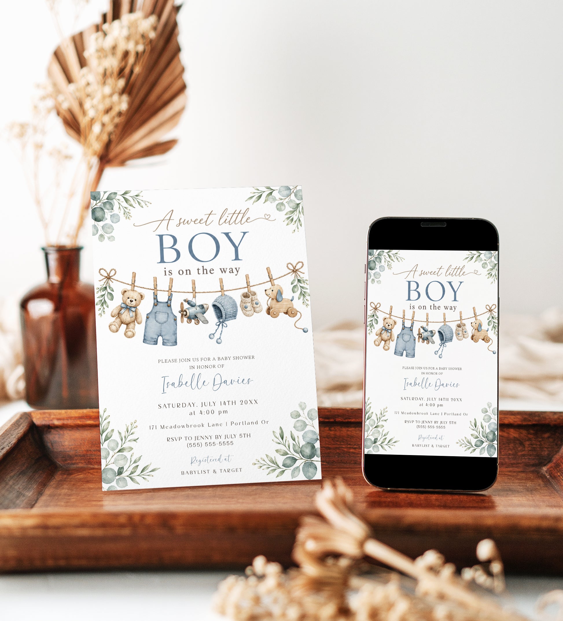 Editable boy baby shower invitation Canva template with watercolour clothesline scene featuring denim overalls, knit bonnet, booties, toy airplane, wooden pull dog, and teddy bear with eucalyptus border on a white background
