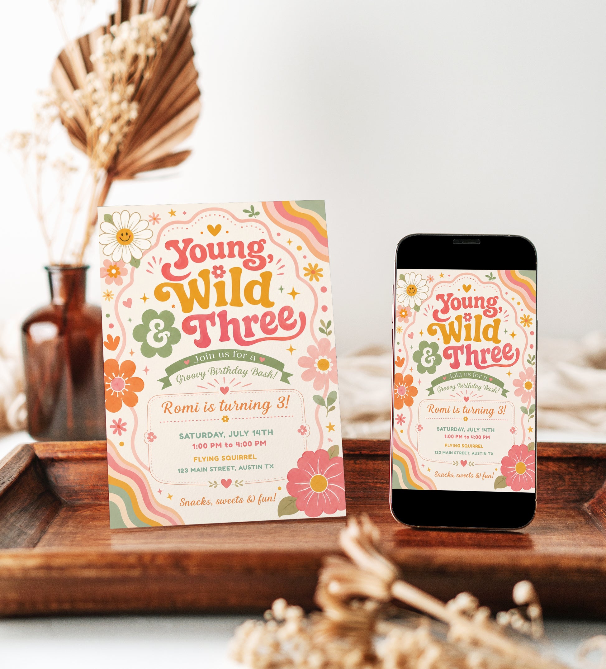 Young wild and three birthday invitation with groovy retro lettering, colorful flowers, rainbow waves, hearts, stars, and boho pink orange sage details