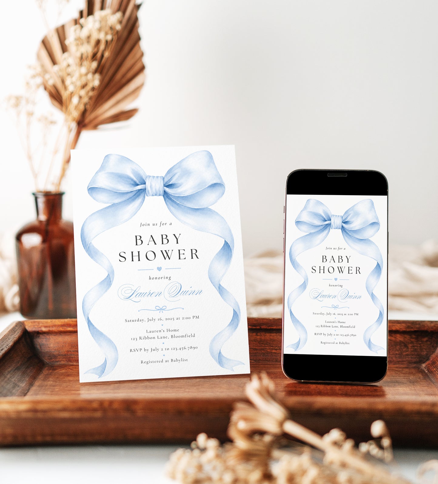 Editable blue bow baby boy shower invitation Canva template with oversized watercolour powder blue bow and flowing ribbon tails, bold spaced serif typography, and blue calligraphy script on a white background