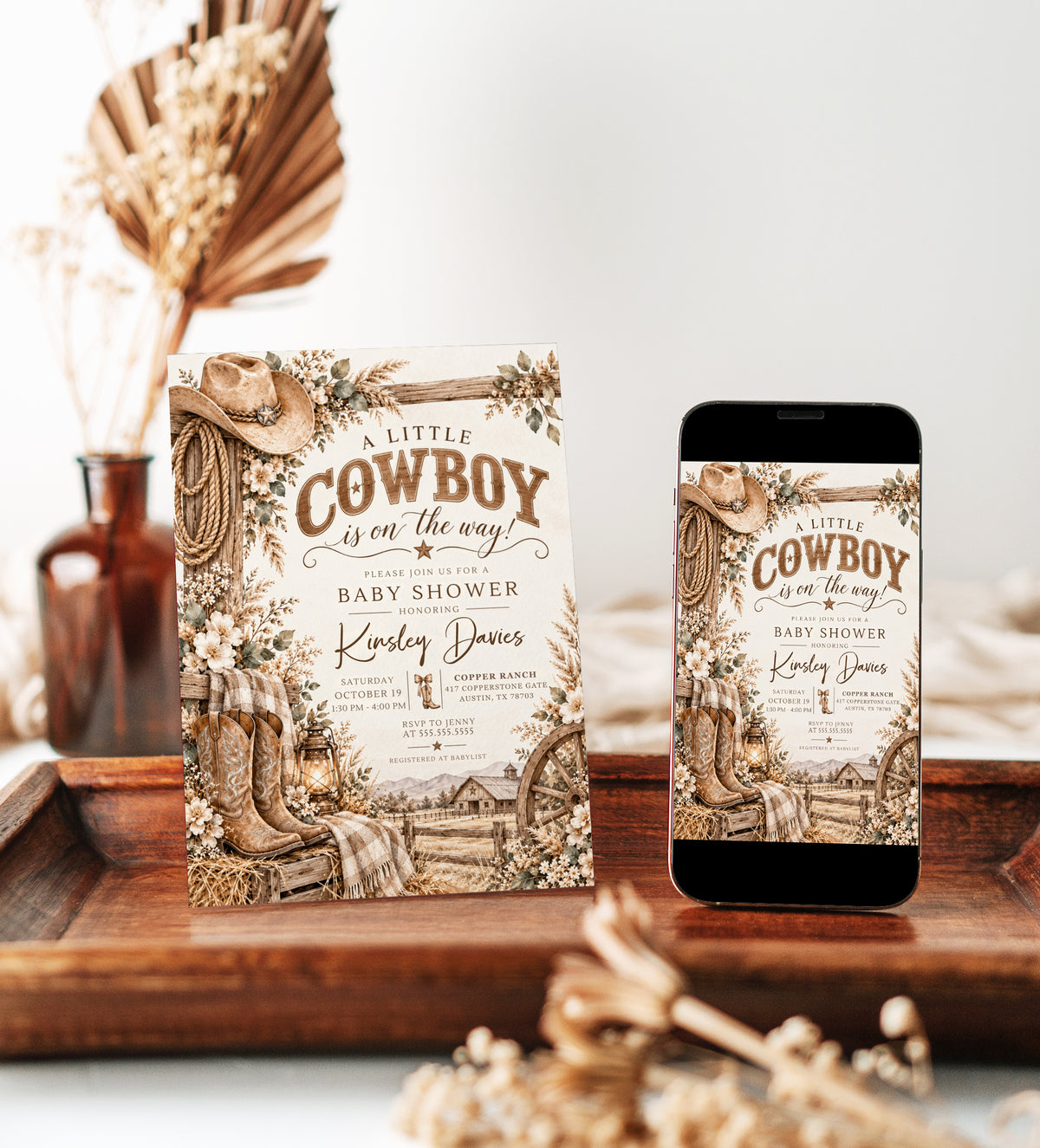 Cowboy baby shower invitation with western boots, cowboy hat, rope, lantern, rustic barn, wagon wheel, and neutral florals in brown tones
