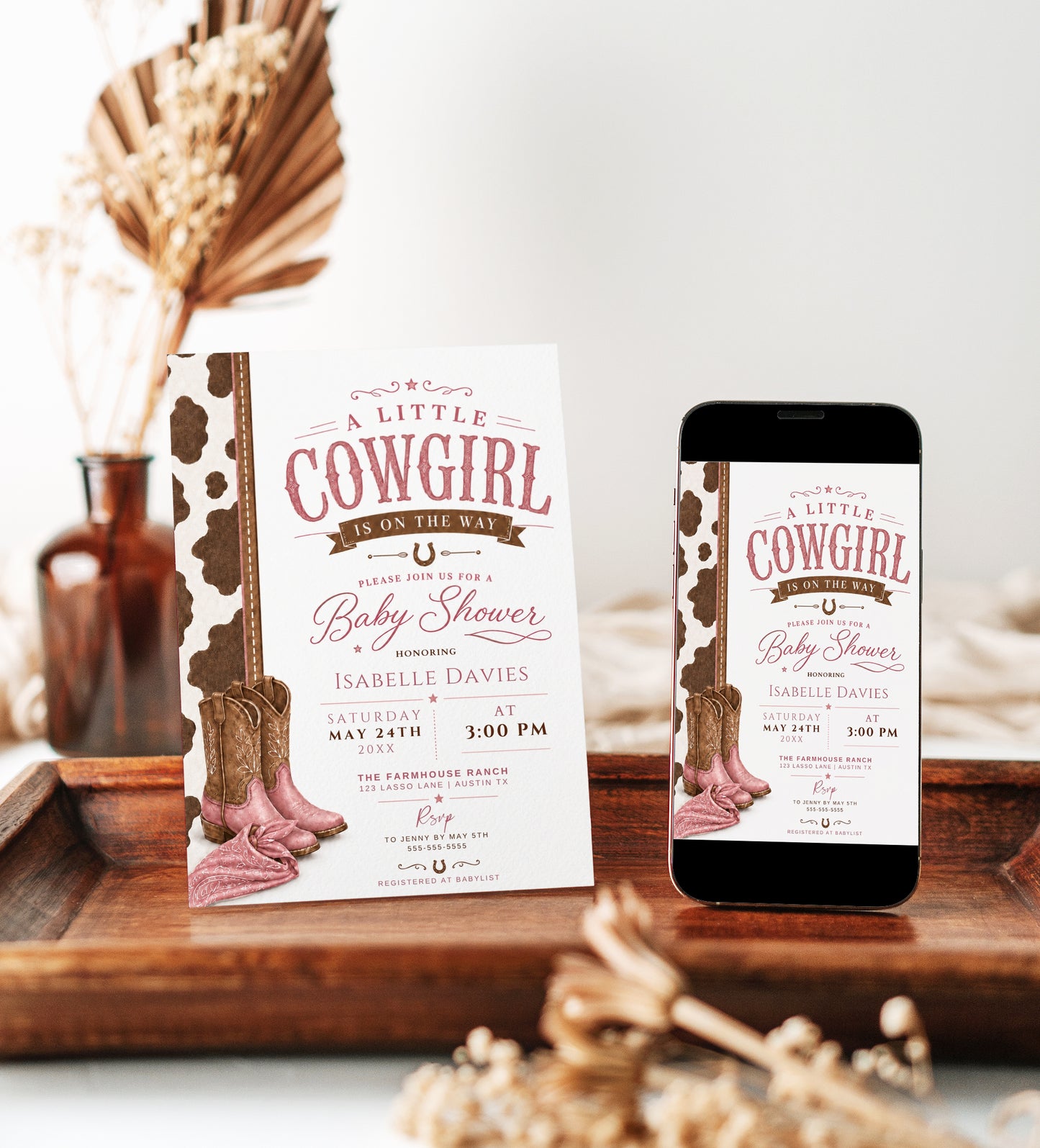 Little cowgirl baby shower invitation featuring pink cowboy boots, a pink bandana, brown cow-print border, horseshoes and western details.
