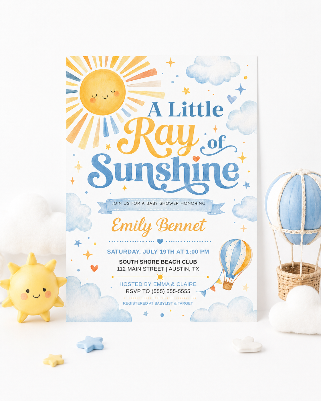 A little ray of sunshine baby shower invitation with golden sun, soft blue clouds, stars, hearts, and a blue and yellow hot air balloon