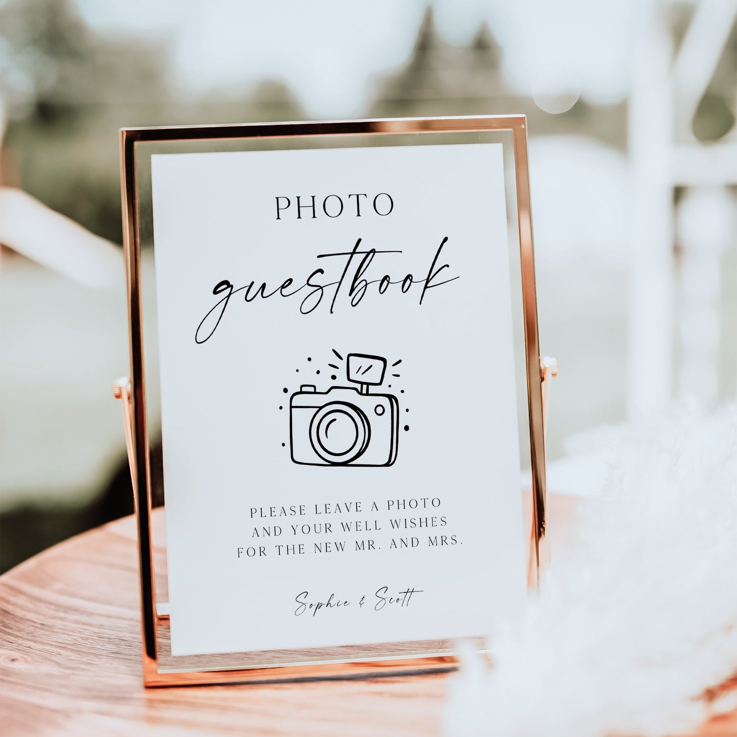 Minimalist black and white wedding photo guestbook sign template with calligraphy script and hand-drawn camera illustration, editable in Canva