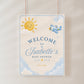 Editable here comes the son baby shower welcome sign Canva template with smiling sun, blue toy airplane, fluffy clouds, arched navy typography, and flowing script on a warm cream background