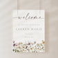 Vertical wildflower baby shower welcome sign template with watercolor meadow flowers in yellow, purple, and cream, editable in Canva