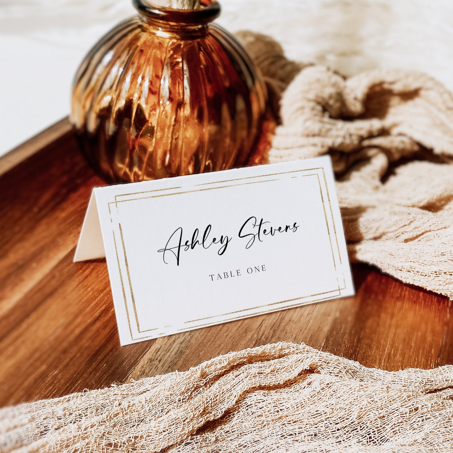 Minimalist wedding place card template with gold double frame border and elegant calligraphy script, editable in Canva