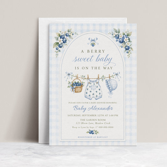 Editable blueberry baby shower invitation Canva template with watercolour blueberry clusters, clothesline scene with romper and bonnet, and blue gingham background, shown with front and back of card