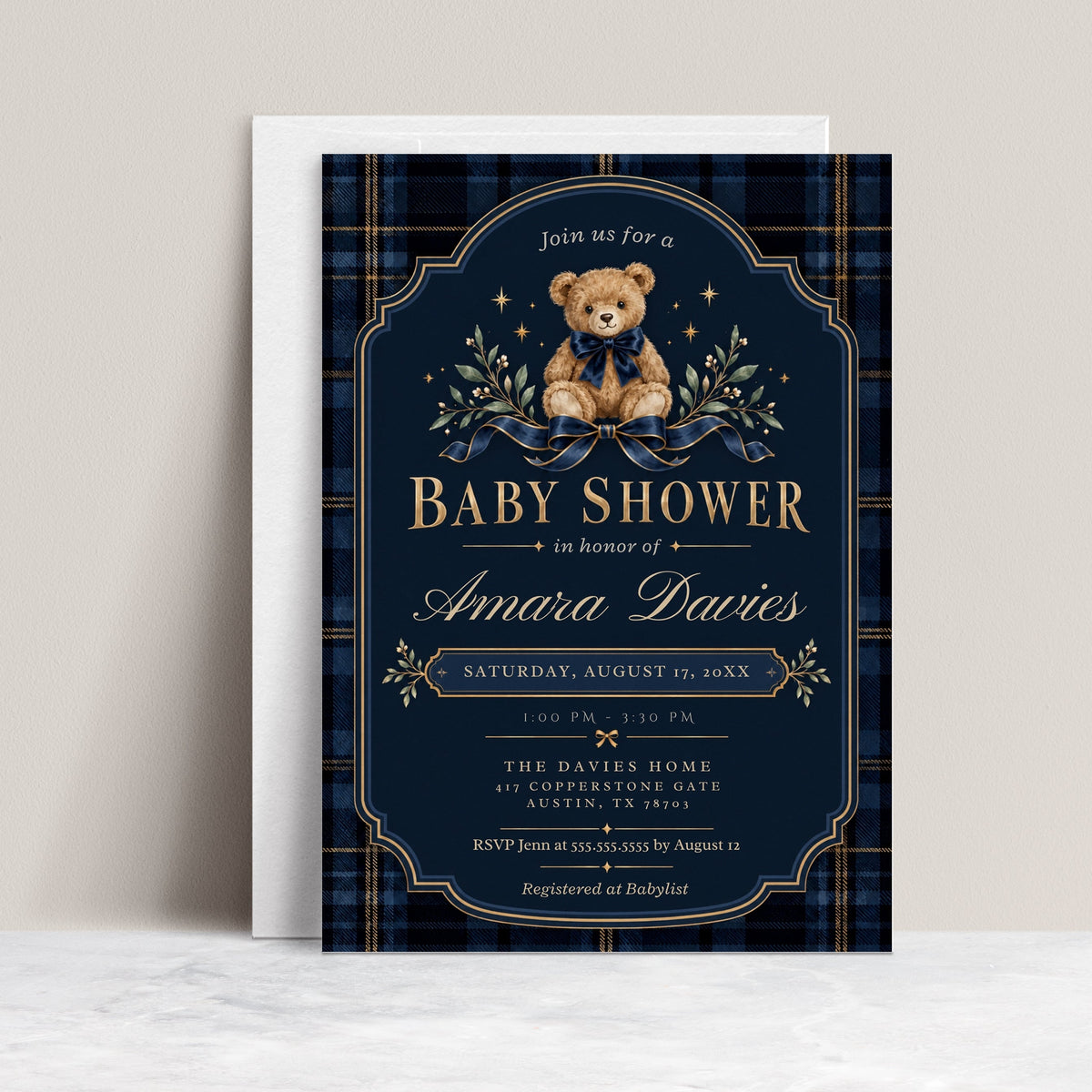 Teddy bear baby shower invitation with a brown bear wearing a navy bow, blue plaid border, gold lettering, stars, and greenery on a dark navy background