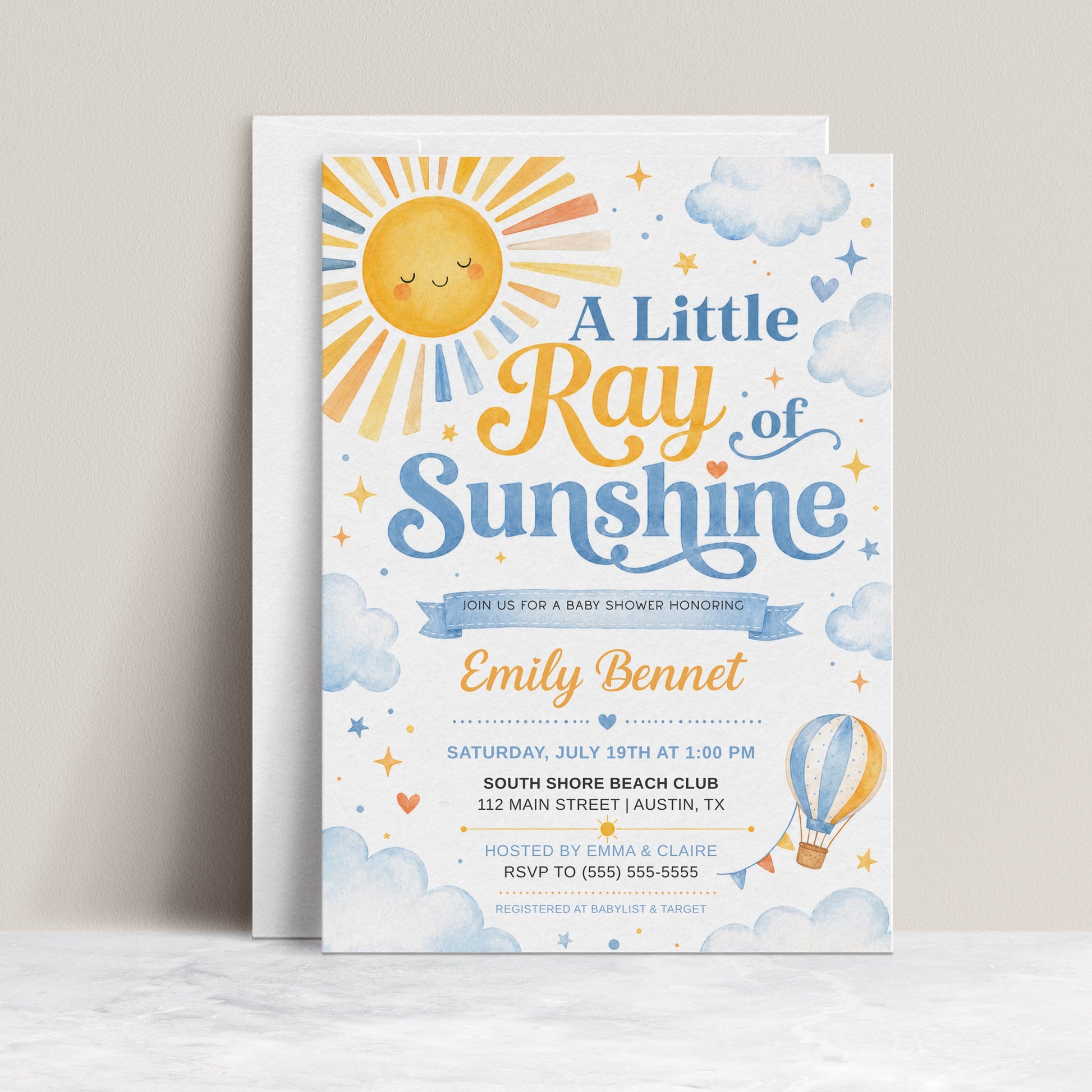 A little ray of sunshine baby shower invitation with golden sun, soft blue clouds, stars, hearts, and a blue and yellow hot air balloon