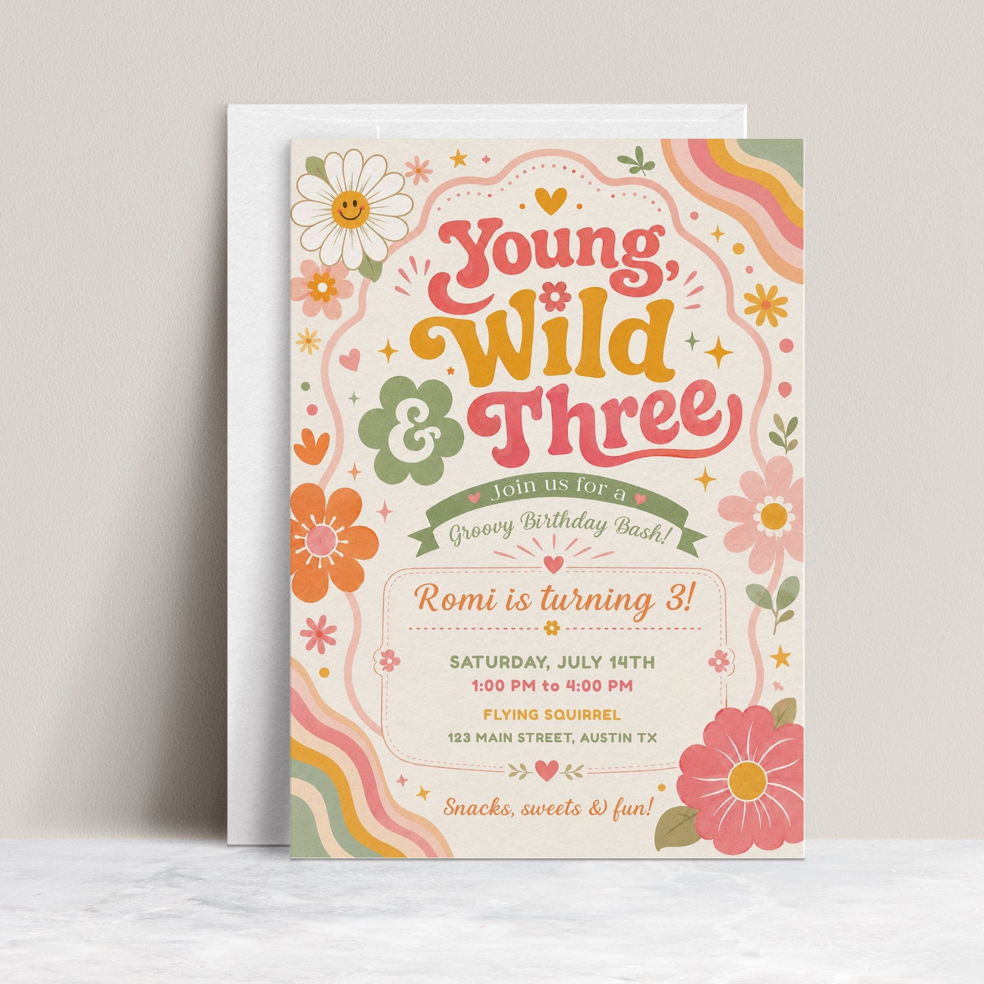 Young wild and three birthday invitation with groovy retro lettering, colorful flowers, rainbow waves, hearts, stars, and boho pink orange sage details