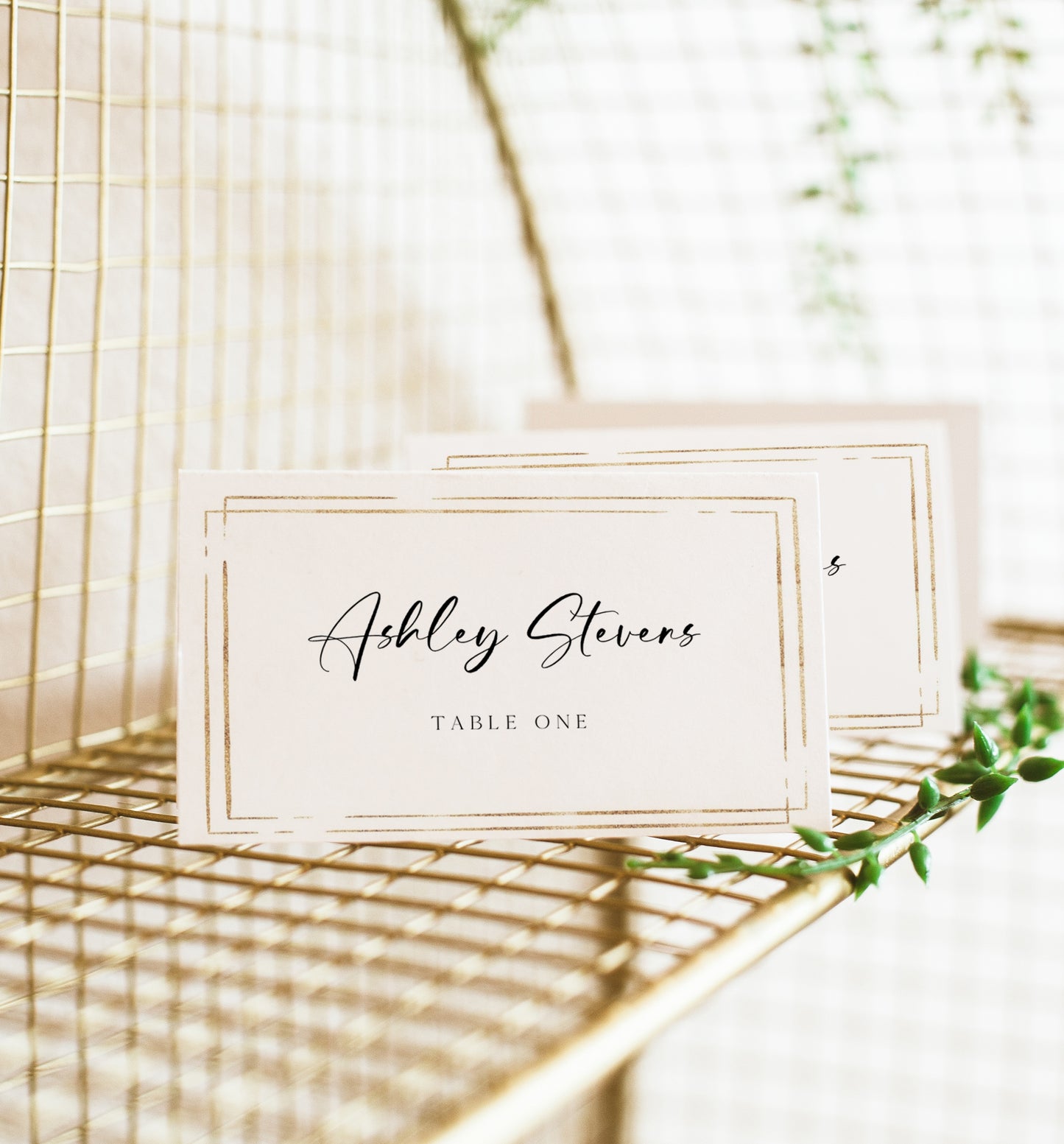 Minimalist wedding place card template with gold double frame border and elegant calligraphy script, editable in Canva