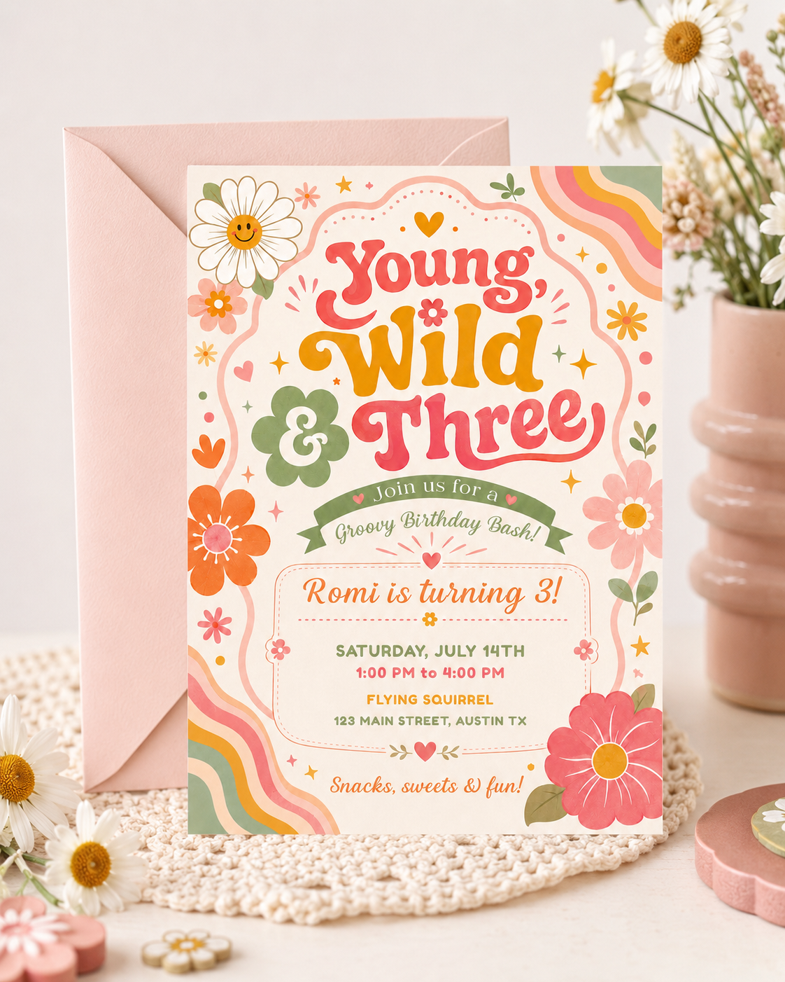 Young wild and three birthday invitation with groovy retro lettering, colorful flowers, rainbow waves, hearts, stars, and boho pink orange sage details