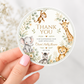 Editable safari baby shower round thank you sticker Canva template with watercolour monkey, giraffe, elephant, lion cub, and zebra in a eucalyptus and tropical leaf wreath on a cream background