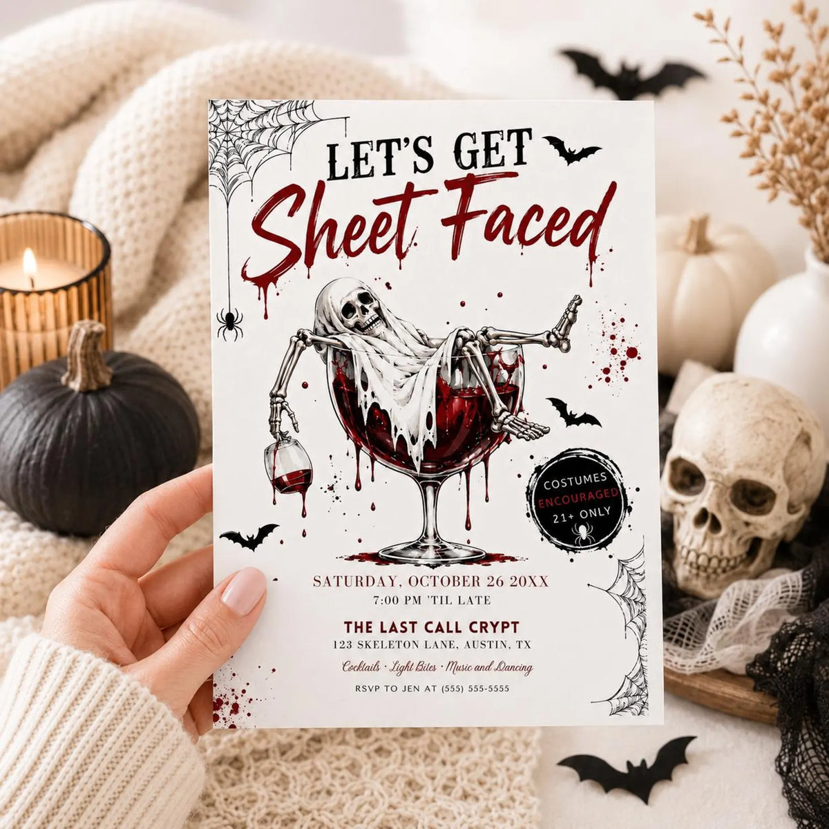 Adult Halloween party invitation with Let’s Get Sheet Faced headline, ghostly skeleton in a red cocktail glass, bats, and spiderwebs